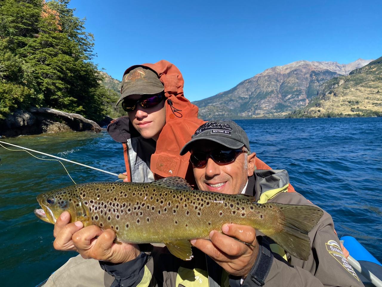 Two guests in a boat with a wild brown trout on a Patagonia lake near Coyhaique