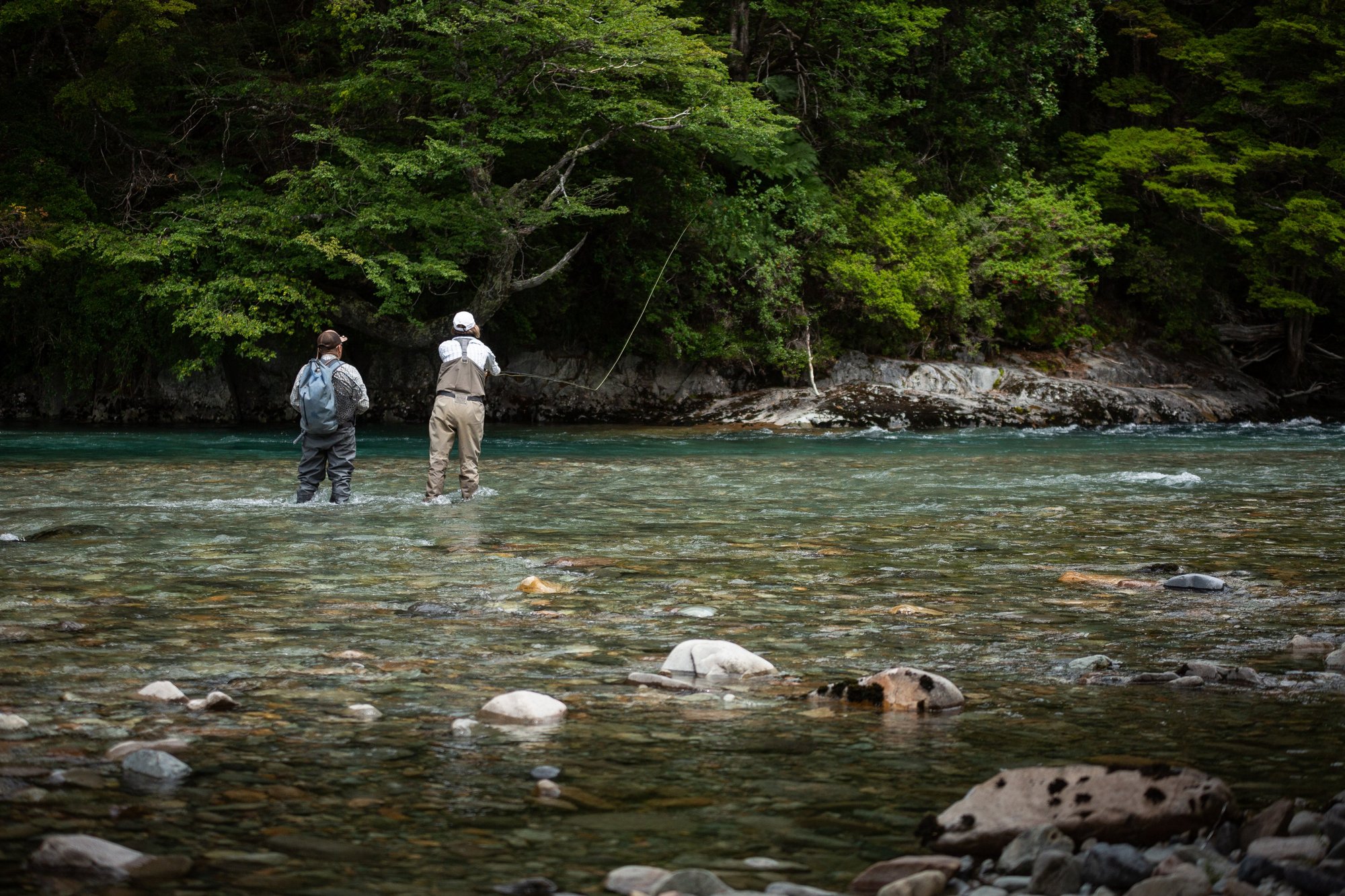 Two anglers wade fishing a turquoise river in Chilean Patagonia
