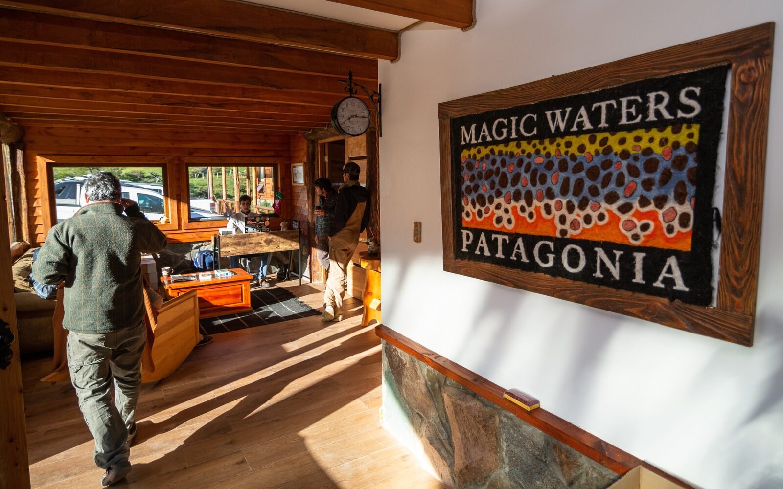 Magic Waters Lodge entrance with MAGIC WATERS PATAGONIA wall art and guests