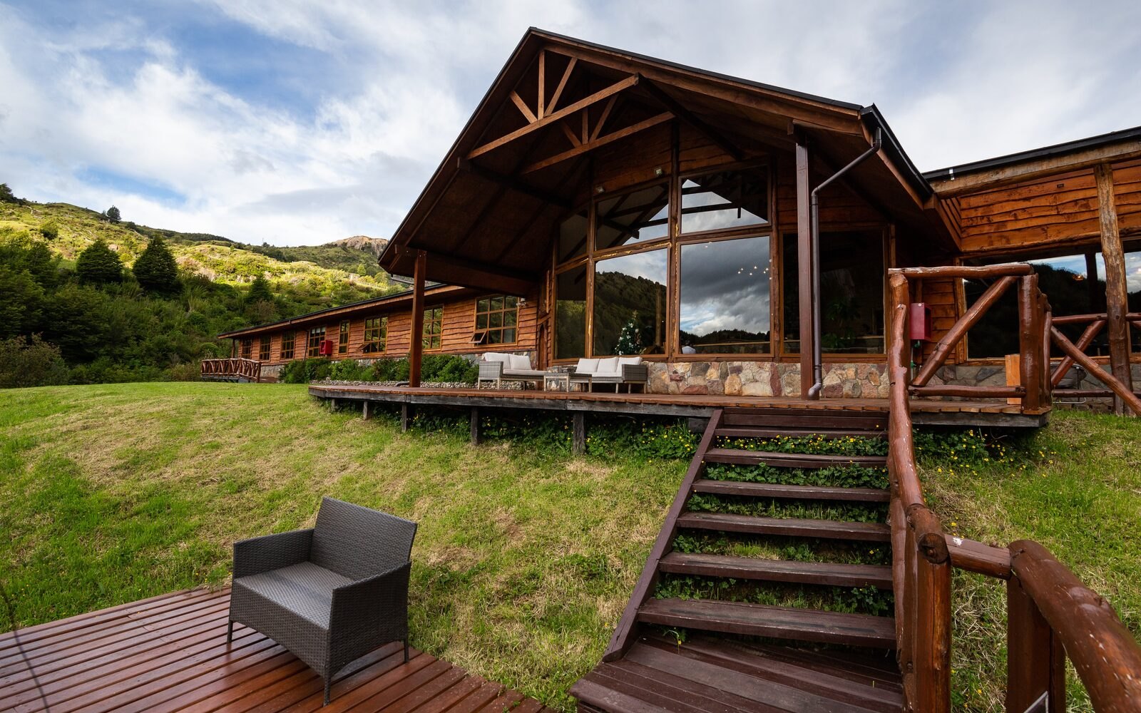 Magic Waters Lodge exterior with large glass front, deck, and stairs near Coyhaique